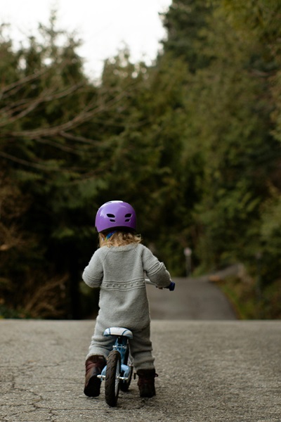 Un enfant sur une draisienne dans une forêt.