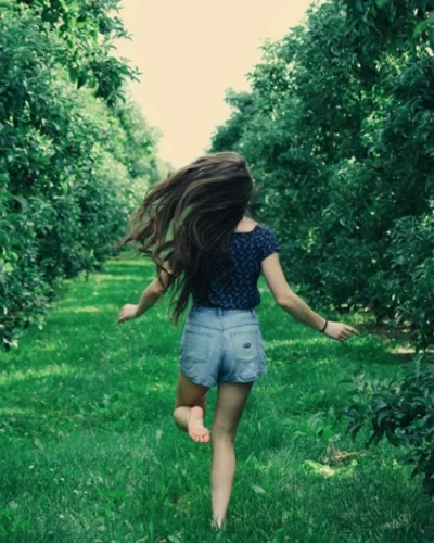 Une fille court dans l'herbe, les pieds nus.